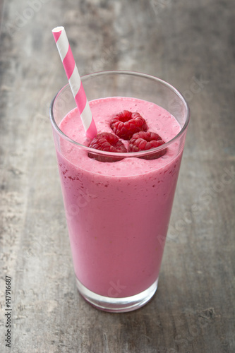 Raspberry smoothie in glass on wooden table 