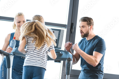 Parents supporting daughter workout on treadmill