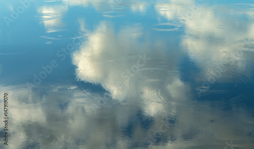 Reflection on the water of clouds decorating a beautirful sky photo