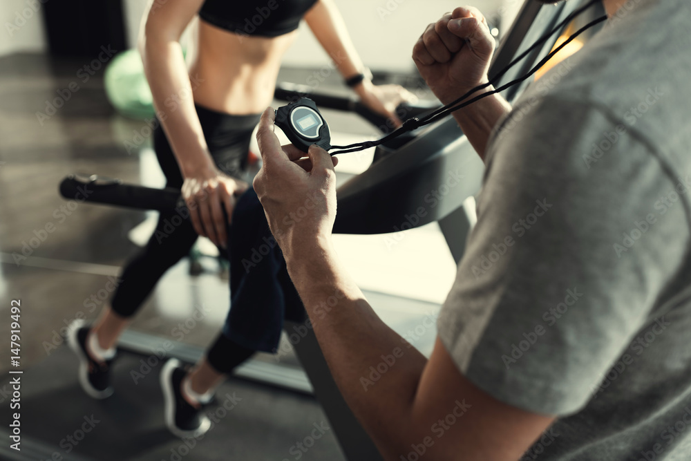 woman workout on treadmill and trainer with timer, side view woman workout on treadmill and trainer with timer, side view