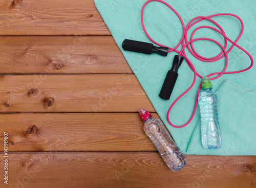 Bottle with towel water and skipping rope on wooden table