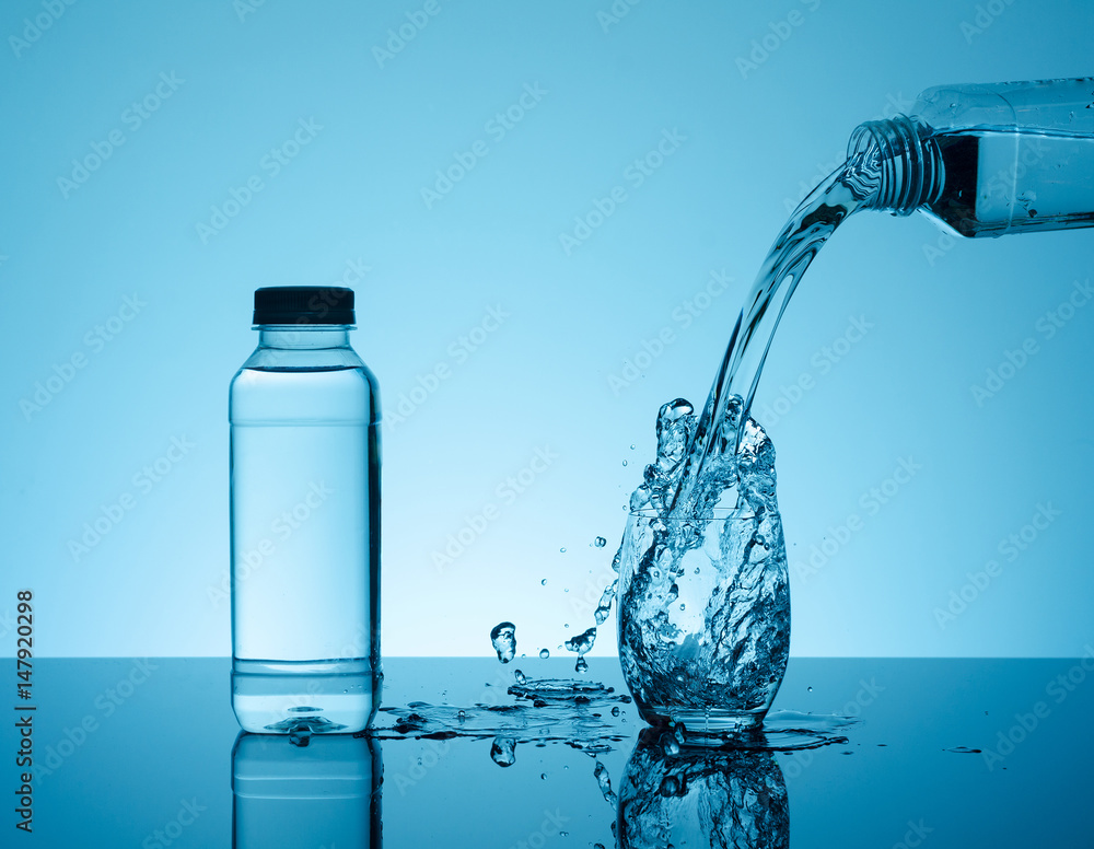 Bottle with creative splashing water in the glass Bottle with creative splashing water in the glass