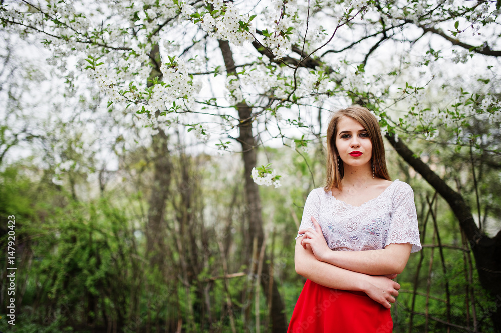 Portrait of beautiful girl with red lips at spring blossom garden, wear on red dress and white blouse. Portrait of beautiful girl with red lips at spring blossom garden, wear on red dress and white blouse.