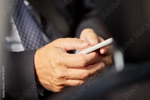 senior businessman texting on smartphone in car