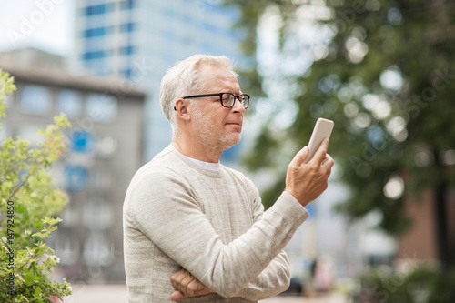 senior man texting message on smartphone in city