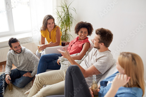 group of happy friends with drinks talking at home
