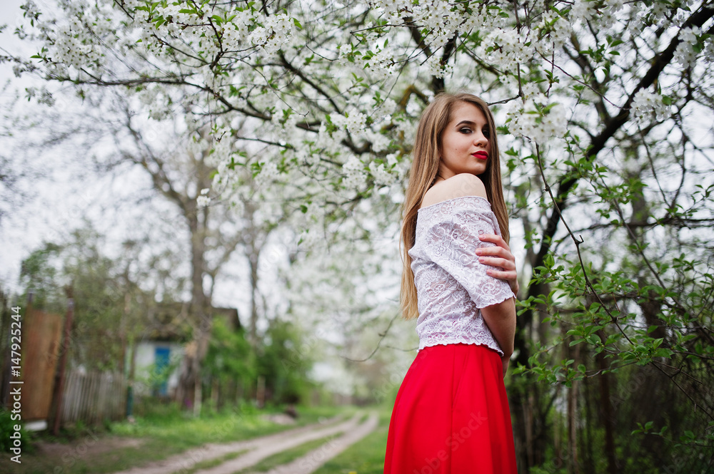 Portrait of beautiful girl with red lips at spring blossom garden, wear on red dress and white blouse. Portrait of beautiful girl with red lips at spring blossom garden, wear on red dress and white blouse.