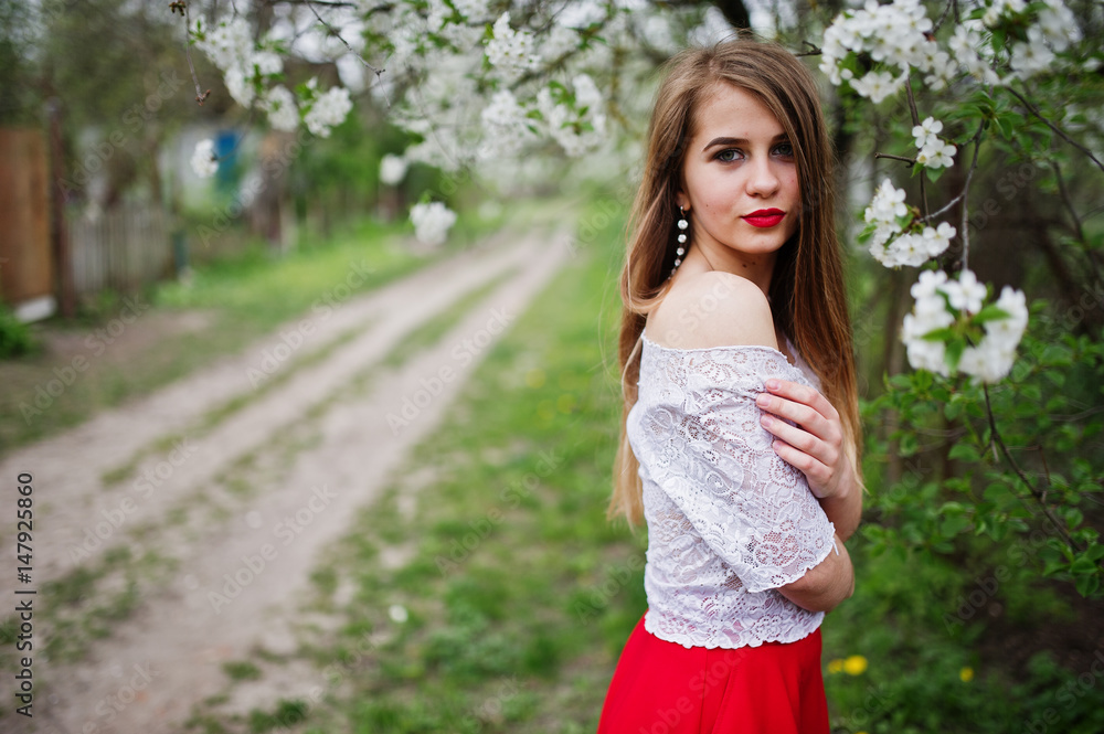 Portrait of beautiful girl with red lips at spring blossom garden, wear on red dress and white blouse. Portrait of beautiful girl with red lips at spring blossom garden, wear on red dress and white blouse.