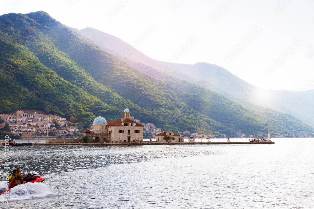 Fjord in Adriatic Sea. Our Lady of the Rock island and Church in Perast on shore of Boka Kotor bay (Boka Kotorska), Montenegro, Europe. Kotor Bay is a UNESCO World Heritage Site