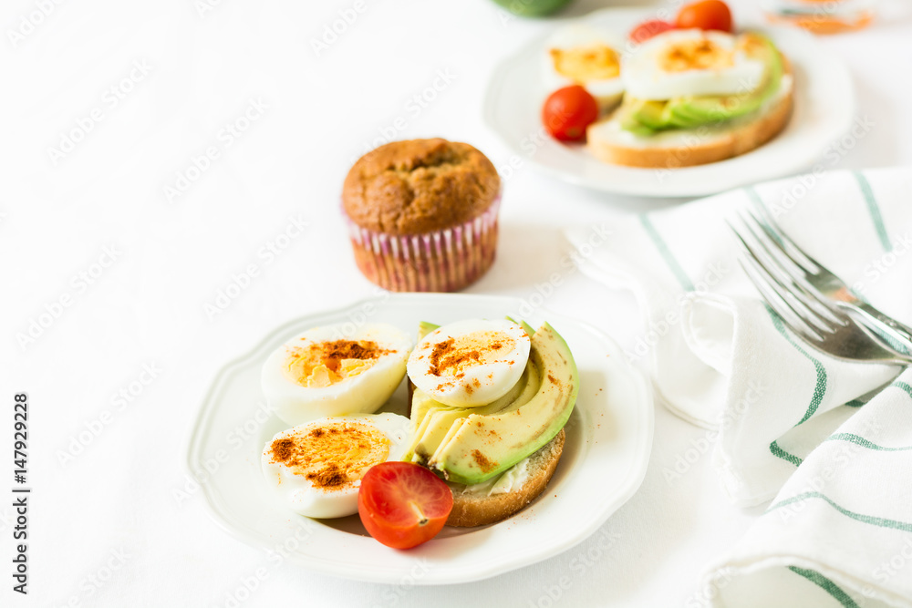 Healthy breakfast: toasts with avocado slices, tomato, paprika and eggs on white tableware. Selective focus Healthy breakfast: toasts with avocado slices, tomato, paprika and eggs on white tableware. Selective focus