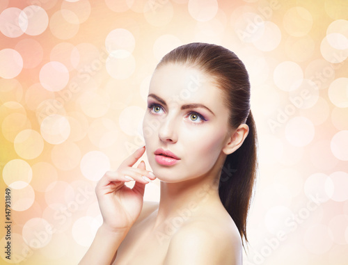 Portrait of young, beautiful and healthy woman: over warm orange background. Healthcare, spa, makeup and face lifting concept.