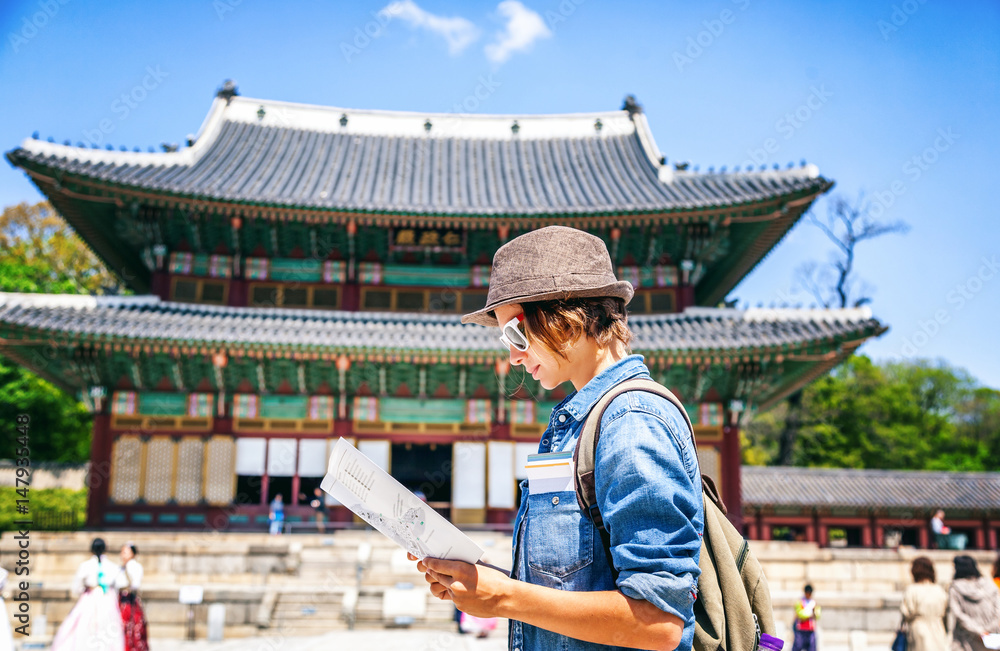 Fototapeta premium Young woman tourist with map in hand on the background of Asian architecture, travel to Korea, Seoul Asia