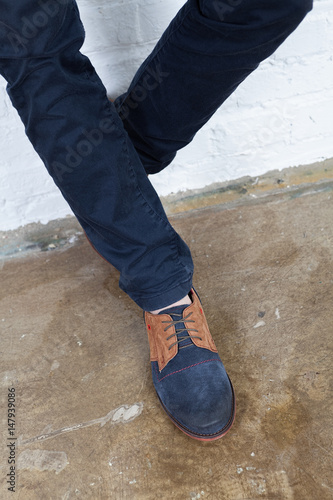 Legs of a young man in a fashionable shoe against the background of the old floor.