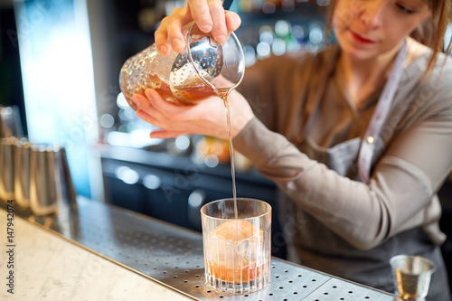 Cuadro en lienzo bartender with glass and jug preparing cocktail