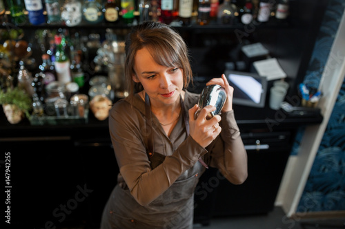 barmaid with shaker preparing cocktail at bar