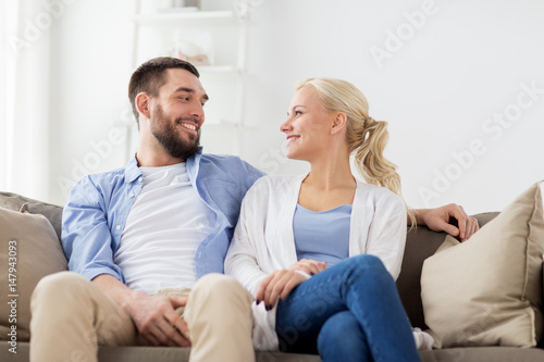 smiling happy couple sitting on sofa at home © Syda Productions