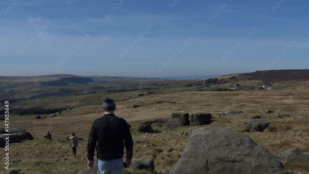 Young couple, man and woman walking on a moor or hill of West Yorkshire, England, United Kingdom Young couple, man and woman walking on a moor or hill of West Yorkshire, England, United Kingdom