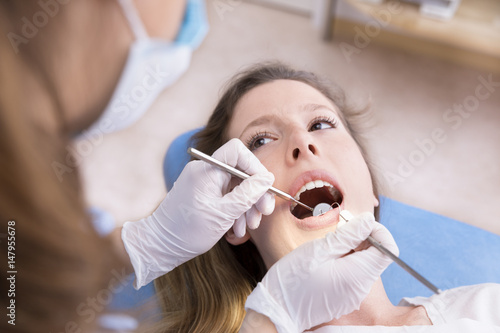 Dentist examining a patient's teeth to the dentist