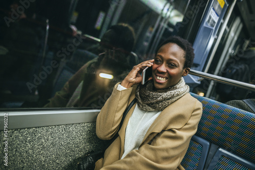 Portrait of smiling young woman on the phone in underground train