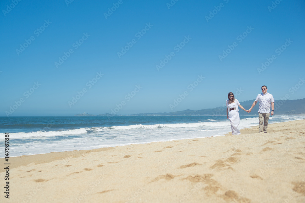 Young romantic couple walking on the beach holding hands Young romantic couple walking on the beach holding hands