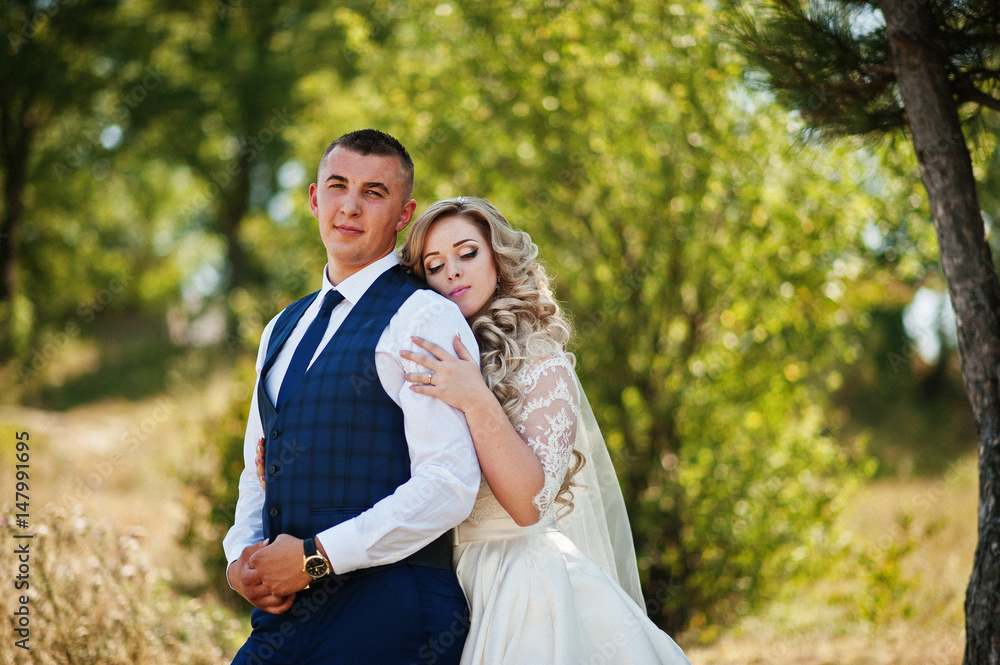 Happy wedding couple in love on sunny day stay near trees. Happy wedding couple in love on sunny day stay near trees.