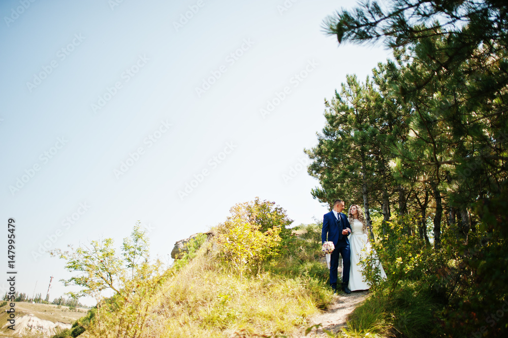 Happy wedding couple in love on sunny day stay near trees.