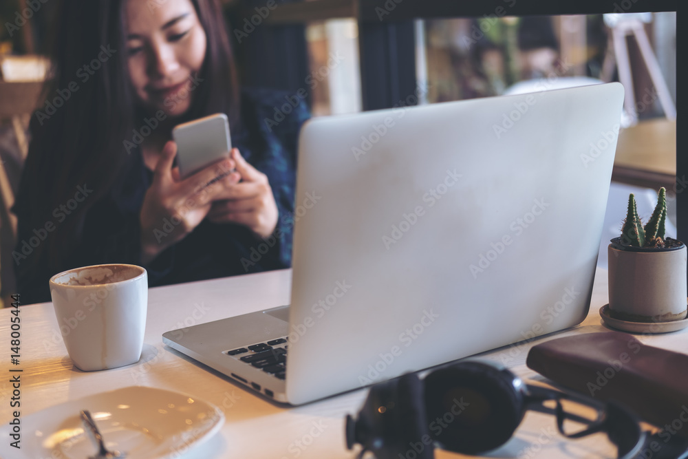A business woman holding and using smart phone and laptop in office A business woman holding and using smart phone and laptop in office