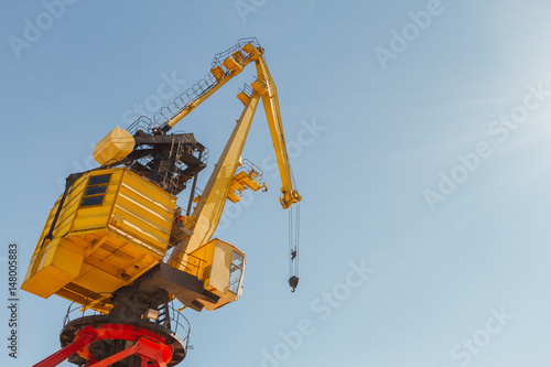 Cargo crane in a harbor with hook against blue sky