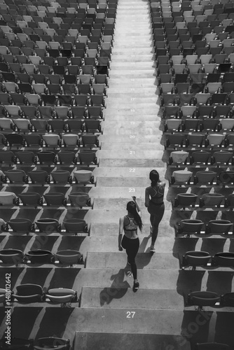 two sportswomen running on stadium stairs, black and white, running women concept