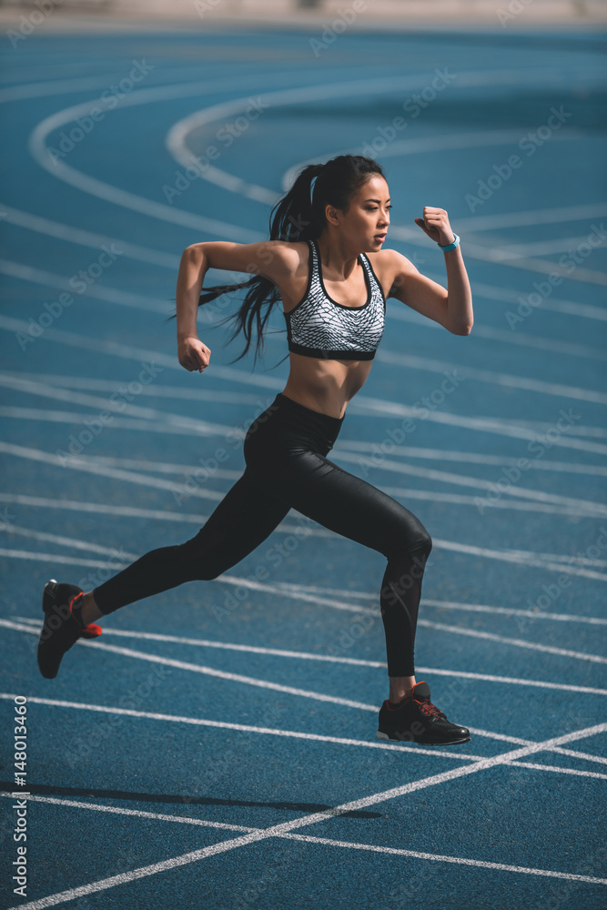Wall Mural asian sportswoman training on running track stadium, young girl running concept