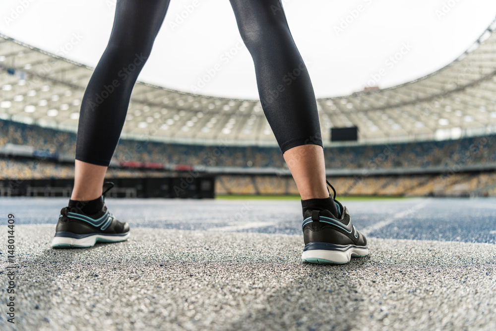 Close-up partial view of young sportswoman in sneakers standing on running track stadium Close-up partial view of young sportswoman in sneakers standing on running track stadium