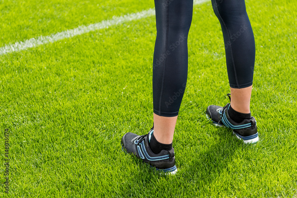 Close-up partial view of sportswoman standing on soccer stadium grass Close-up partial view of sportswoman standing on soccer stadium grass