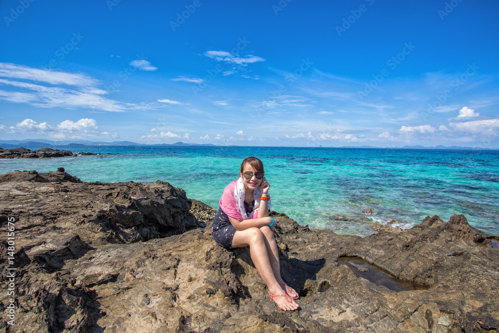 woman in dress sitting on a stone by the sea