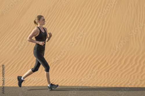 woman drinking water after a run in a desert © katiekk2