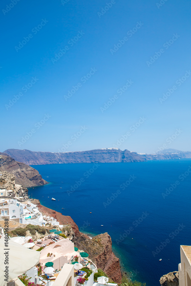 View of Fira town - Santorini island,Crete,Greece. White concrete staircases leading down to beautiful bay with clear blue sky and sea