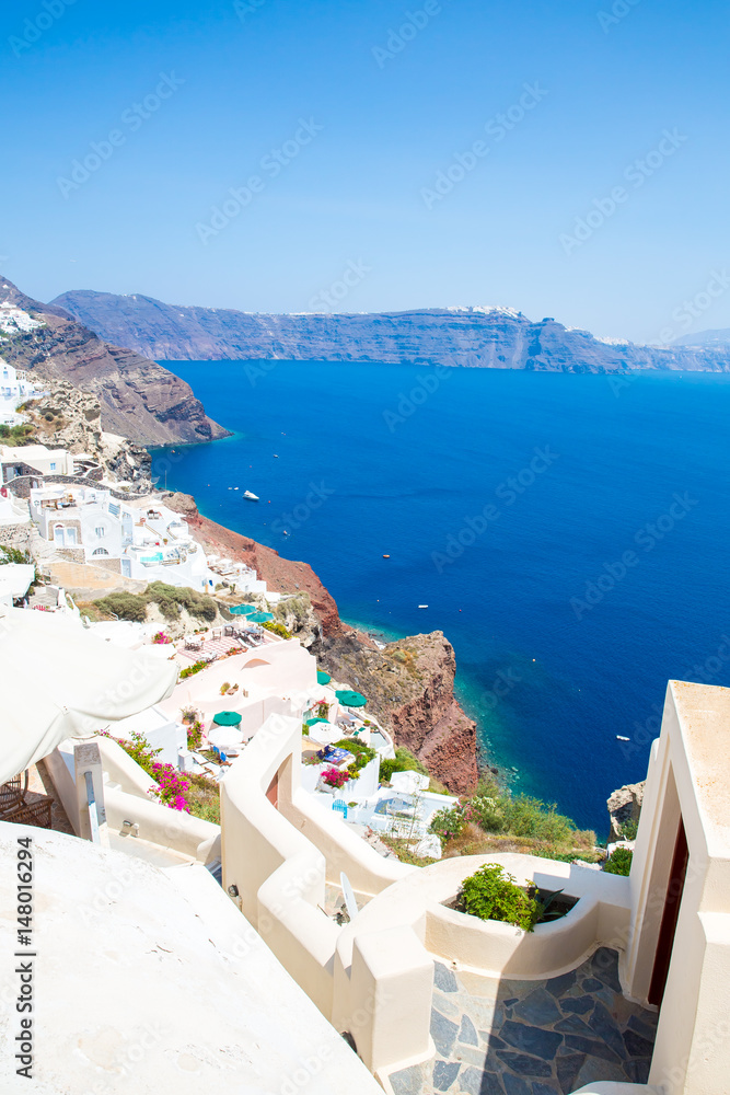 View of Fira town - Santorini island,Crete,Greece. White concrete staircases leading down to beautiful bay with clear blue sky and sea