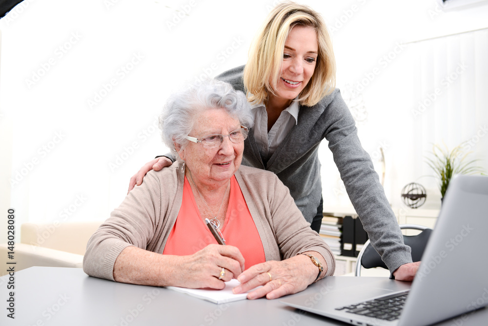 attractive 40 years old woman helping with computer her mother for internet search , 80 years old senior woman at home attractive 40 years old woman helping with computer her mother for internet search , 80 years old senior woman at home