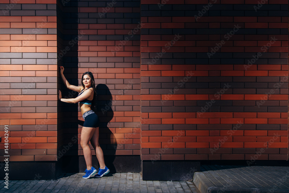 Attractive young woman in sportswear posing against a brick wall background with copyspace. Training outdoors. Attractive young woman in sportswear posing against a brick wall background with copyspace. Training outdoors.