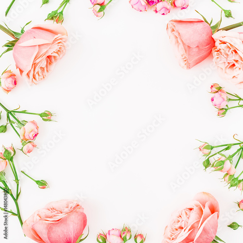 Round frame made of beautiful pink roses  buds and leaves on white background. Flat lay  top view. Floral pattern