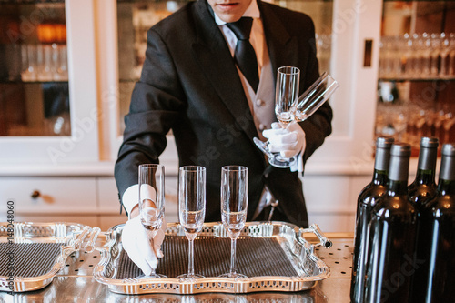 Waiter placing champagne flutes on silver tray  photo