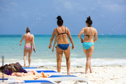 Group of young women walking on the beach. They are heading to the sea.