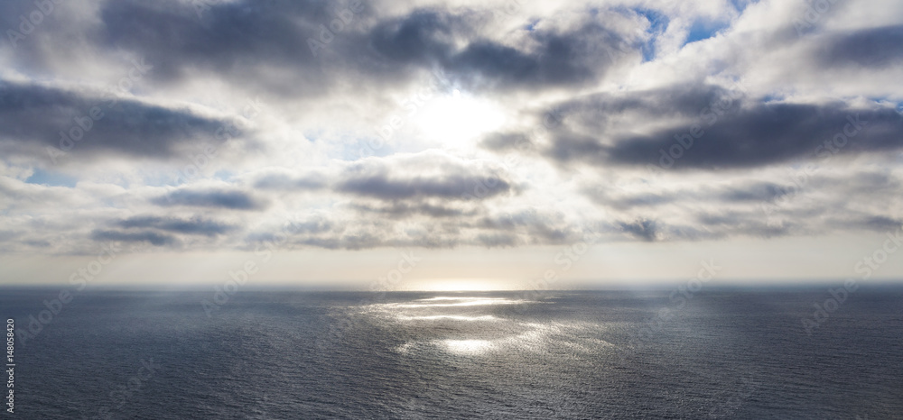Obraz premium Breakthrough of light in clouds over a calm sea