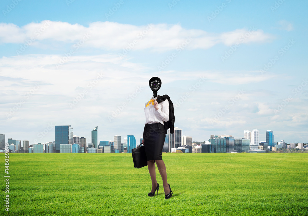 Camera headed woman standing on green grass against modern cityscape