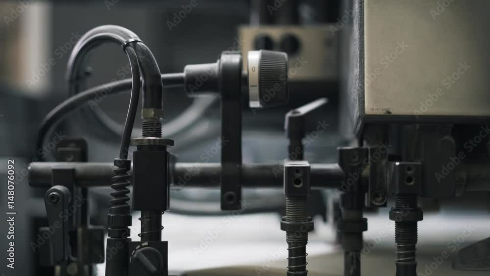 Close up of a typography machine working at a factory with long sheets of paper. Tilt down slow motion close up shot Close up of a typography machine working at a factory with long sheets of paper. Tilt down slow motion close up shot