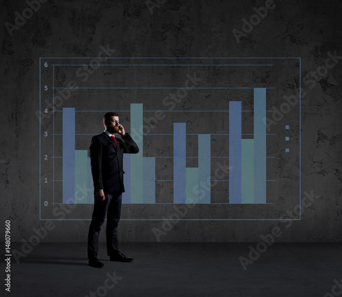 Businessman with smartphone standing over column diagram background. Business, office, career, job concept.