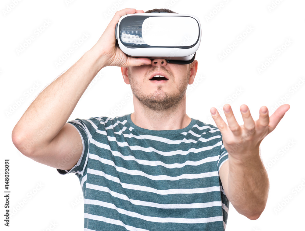 Naklejka premium Amazed man wearing virtual reality goggles watching movies or playing video games gesticulating hands, isolated on white background. Surprised male looking in VR glasses.