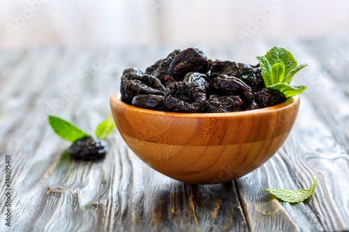 Prunes and mint in a wooden bowl. photo