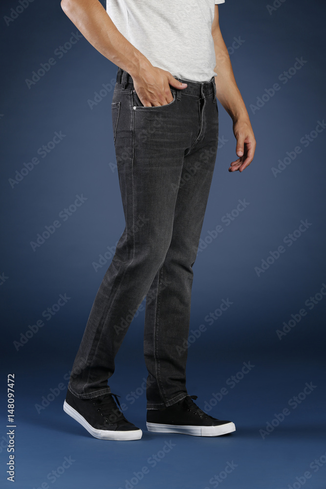 Young fashion man's legs in jeans and sneakers on blue background Young fashion man's legs in jeans and sneakers on blue background