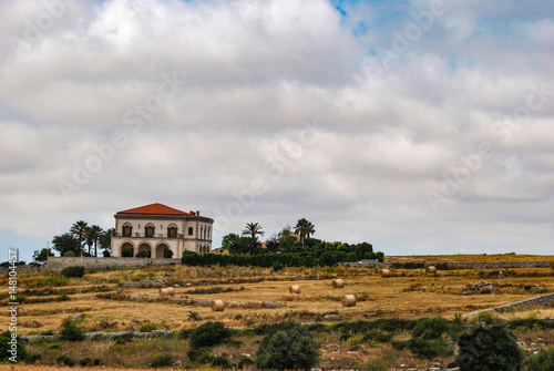 Ragusa, Italy - June 02, 2010: Rural villa in the countryside of Ragusa with the typical dry stone walls and hay bales