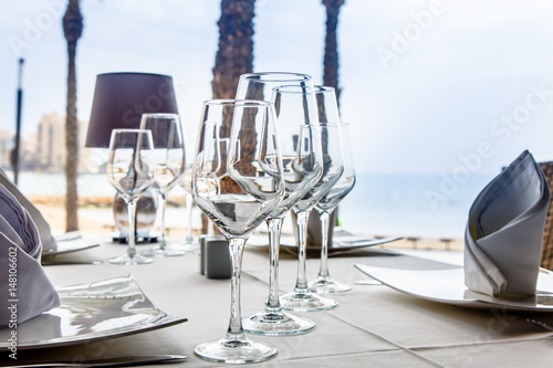 Wineglasses for wine stand on table with white tablecloth waterfront restaurant.